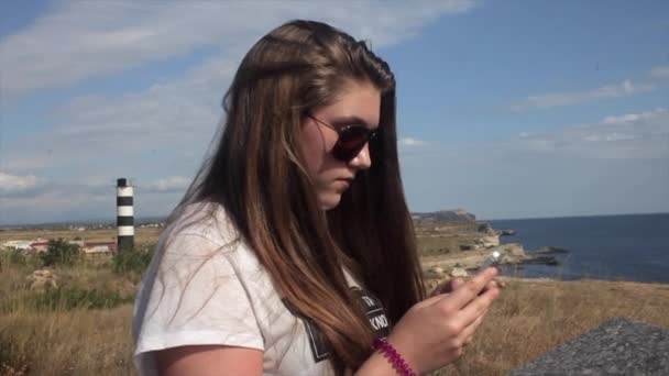 Adolescente chica usando smartphone en la playa . — Vídeos de Stock