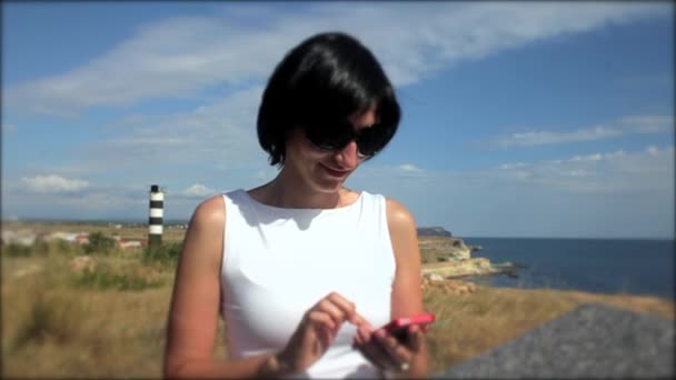 Menina adolescente usando smartphone na praia . — Vídeo de Stock