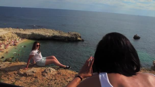 Happy women taking photo friend with smartphone on the background sea lighthouse — Stock Video