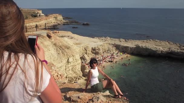 Happy women taking photo friend with smartphone on the background sea lighthouse — Stock Video