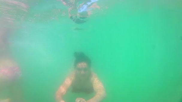 Молодая девушка-подросток плавает к нам под водой — стоковое видео