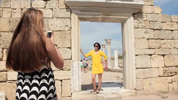 古代都市背景の廃墟の上のスマート フォンで写真のガール フレンドを取って幸せな女性 — ストック動画