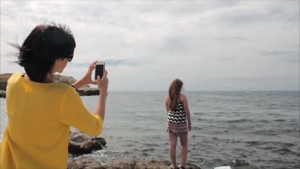 Feliz mamá tomando la foto de su hija con el teléfono inteligente en el fondo ver — Vídeos de Stock