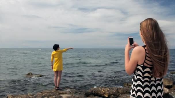 Happy mom taking photo your daughter with smartphone on the see background — Stock Video