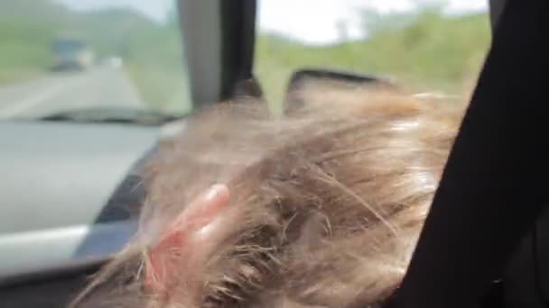 Вітер дме крізь волосся дівчат. Втомлена дівчина-підліток спить в машині — стокове відео