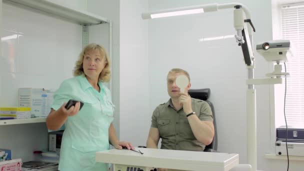 Hombre examinando sus ojos por un oftalmólogo — Vídeos de Stock