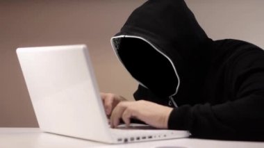 Siyah başlıklı bir dizüstü bilgisayar ile anonim hacker