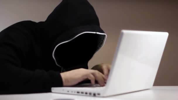 Anonymous hacker in black hood with a laptop — Stock Video