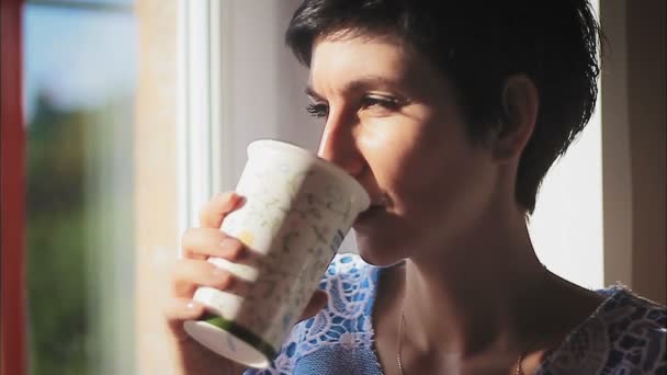 Beautiful woman sipping hot steaming drink — Stock Video