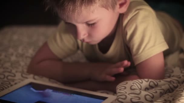 Kleine jongen kijken verhalen op Tablet PC op bed — Stockvideo