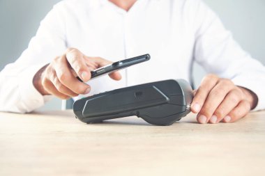 Pos terminali ve beyaz arka planda akıllı telefonu olan bir el bilgisayarı. Banka ekipmanları. Ediniyorum. Banka kredi kartlarının kabul edilmesi. Temassız ödeme.