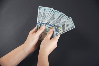 Siyah arka planda 100 dolarlık banknotlar sayan eller