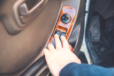 Adam otomobildeki güç kolunu kaldırarak cam kaldırıyor, el ve parmak görüntüsünü yakından görüyor, uzaktan kumanda ediyor.