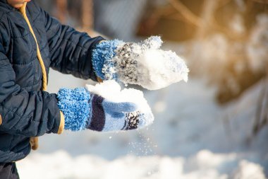 Küçük çocuk kar yağarken yürüyüp taze karla oynayarak eğleniyor.