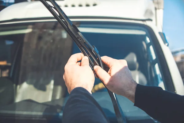 Technician is changing windscreen wipers on a car station