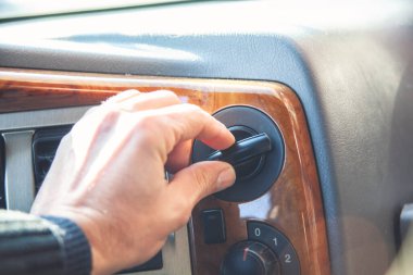 Genç adam arabanın klimasını açıyor.