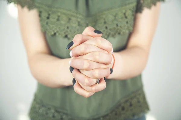 Praying woman\'s hands isolated on grey background.