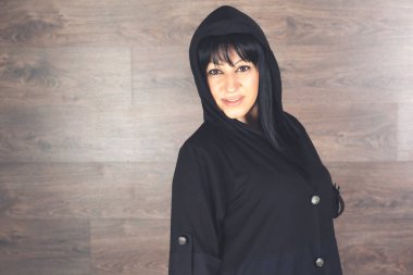 Stüdyoda siyah saçlı, gülümseyen güzel bir genç kadın..