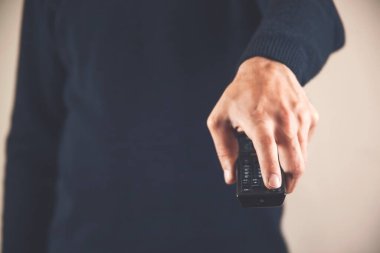 Bir adam uzaktan kumandasını elinde tutuyor. Adam kanalları değiştirip ne izleyeceğini seçiyor. Eğlence ve eğlence konsepti