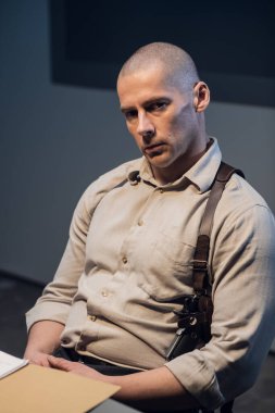 Kel dedektif sorgulamadan sonra yoruldu, portre çizdi. Karanlık bir odada elinde silahla vahşi bir adam dramatik bir ışıkla..