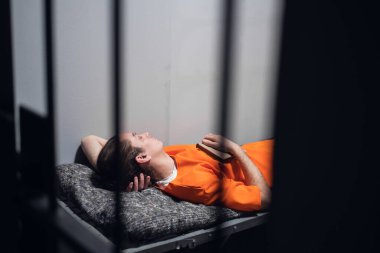 Hücredeki tehlikeli bir mahkum turuncu bir cüppeyle tek kişilik bir hücrede dinlenir ve uyur..