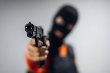 Tabanca, maskeli bir haydut teröristin yüzünü yakından takip ediyor.