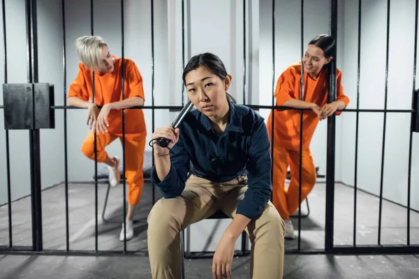 Retrato de un guardia de seguridad asiático en el fondo de dos lindos criminales en las celdas — Foto de Stock