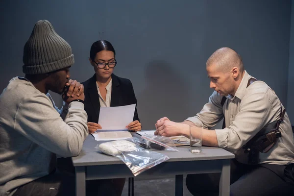 Una hermosa abogada con gafas se familiariza con la evidencia durante el interrogatorio de su cliente, un drogadicto negro. — Foto de Stock