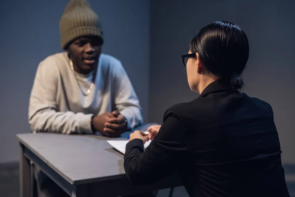 Egy fekete fickó meghallgatja a jogait egy civil ügyvédtől, aki egy látogatószobában ül egy állami börtönben. — Stock Fotó