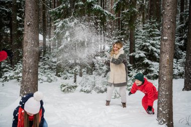 Kar ormanlarında kar topu oynayan bir aile.