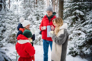 Çocukları olan genç ve güzel bir çift, yeni yıl boyunca ya da Noel tatillerinde muhteşem bir kış ormanında yürürler. Termostan çıkan sıcak çayla ısınıyorlar..