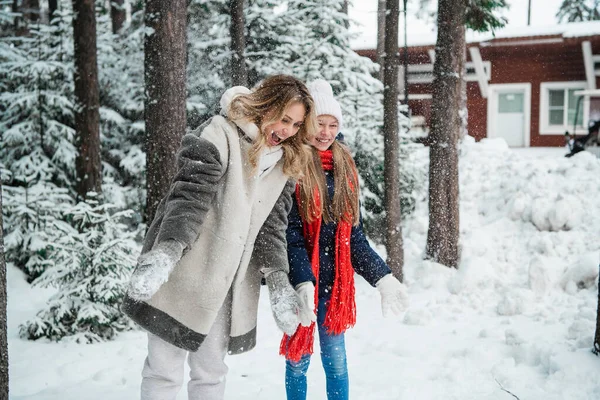 Linda chica adolescente y su madre juegan con la nieve durante un paseo de invierno en el bosque —  Fotos de Stock