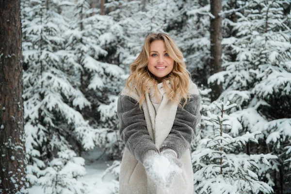 Retrato de invierno de una hermosa rubia rusa con el pelo largo de pie en una nevada en el bosque. — Foto de Stock