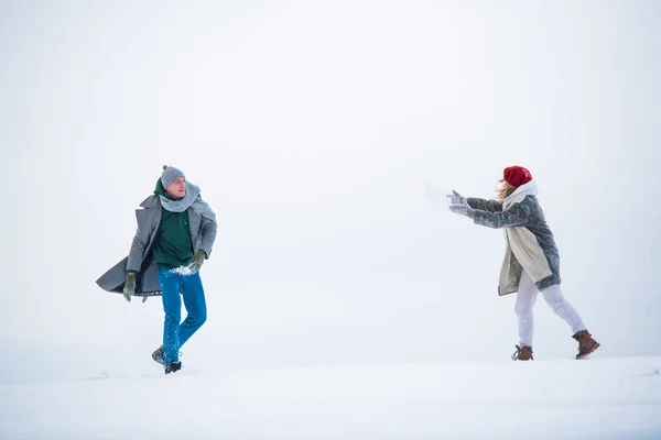 В зимнем снежном поле двое молодоженов играют друг с другом, играют со снегом — стоковое фото
