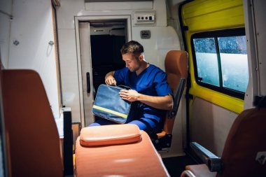 Nöbetçi bir tıp çalışanı, ambulansta sağlık çantasında bir şey var mı diye bakıyor.
