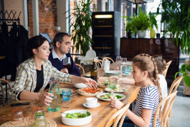 Gülümseyen aile mutfakta birlikte yemek yiyor.
