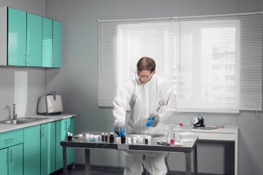 Laboratuarda kimyasal test yapan genç bir araştırmacı.