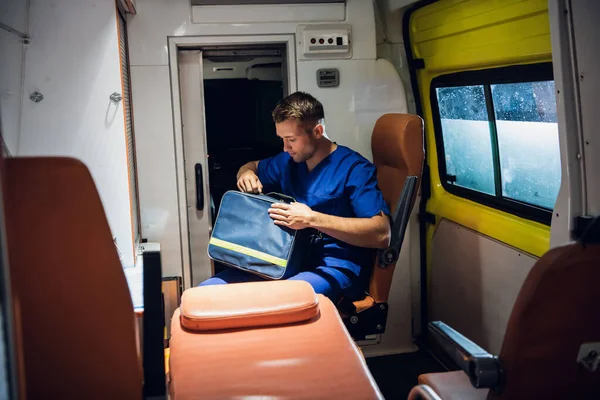Travailleur médical en service, cherchant quelque chose dans sa trousse médicale dans une ambulance — Photo