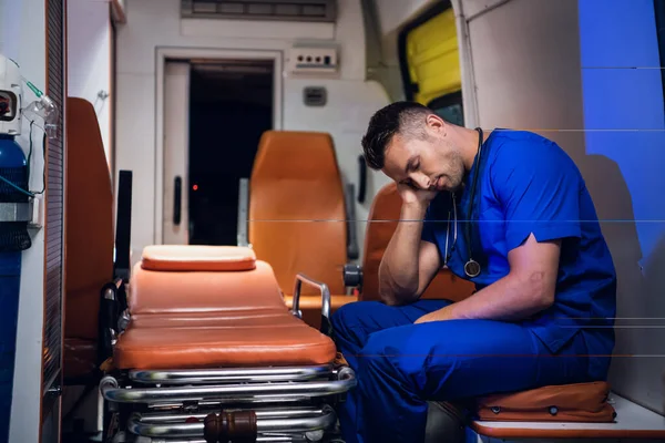 Вымотанный парамедик спит в машине скорой помощи — стоковое фото