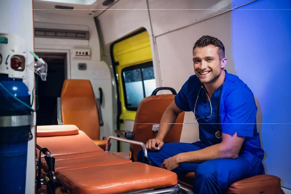 Jovem paramédico positivo de uniforme azul de plantão — Fotografia de Stock