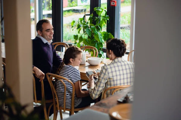 Une famille heureuse échangeant des cadeaux à une grande table à manger — Photo