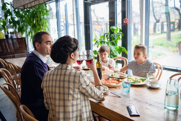 Une famille de quatre personnes lève des verres au dîner dans un café — Photo