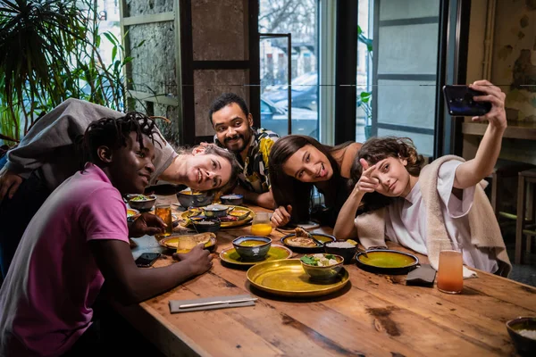 Cinq jeunes amis assis à la table dans un café, prenant selfie — Photo