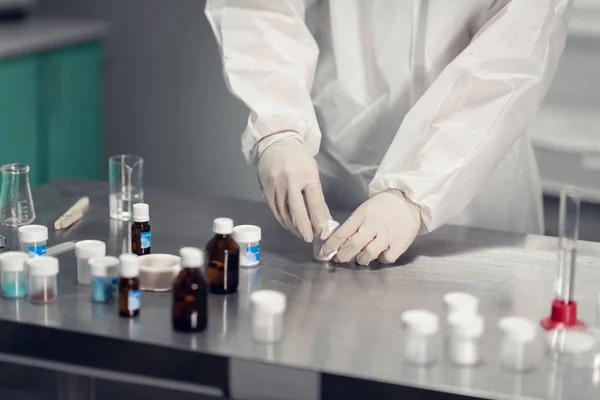Close-up de um homem estudando uma reação química em uma mesa de laboratório com ferramentas de laboratório e líquidos coloridos — Fotografia de Stock
