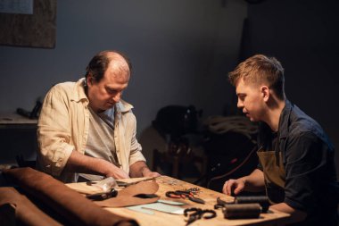 Deneyimli bir ayakkabıcı ve asistanı atölyelerinde deriden siparişe ayakkabı yapıyorlar..