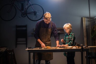 Genç bir baba, garajda oğluna marangozluğu öğretiyor..