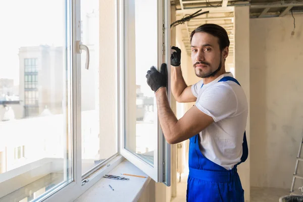 Byggaren står vid det öppna fönstret — Stockfoto