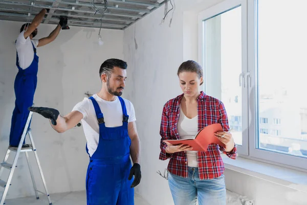 Il supervisore controlla il lavoro dei riparatori nell'appartamento e scrive una nota — Foto Stock