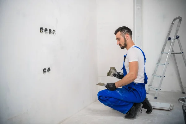 Een bouwer brengt cement aan op de muur om de tegels te bevestigen — Stockfoto