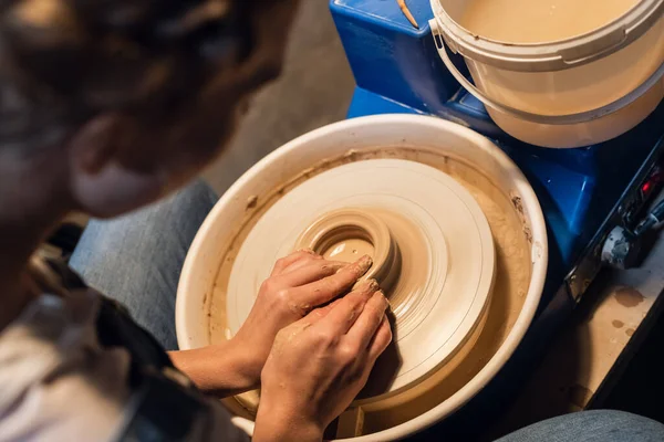 Master class on sculpting a pot in an art workshop. the girl behind the potters wheel makes a blank with her hands. — Stock Photo, Image